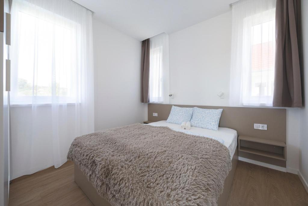 a bedroom with a large bed with two windows at Villa Oliver Kehidakustány in Kehidakustány