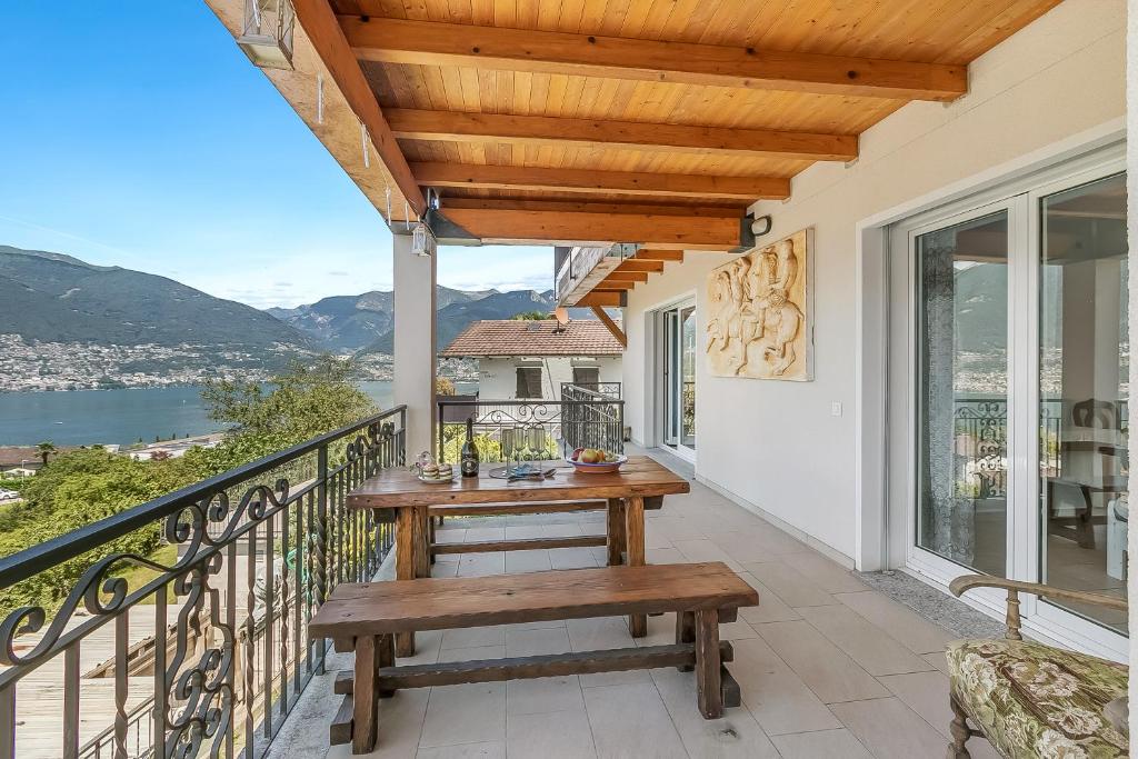 a patio with a wooden table and bench on a balcony at Gambarogno Vista Bella 1 - Happy Rentals in Piazzogna