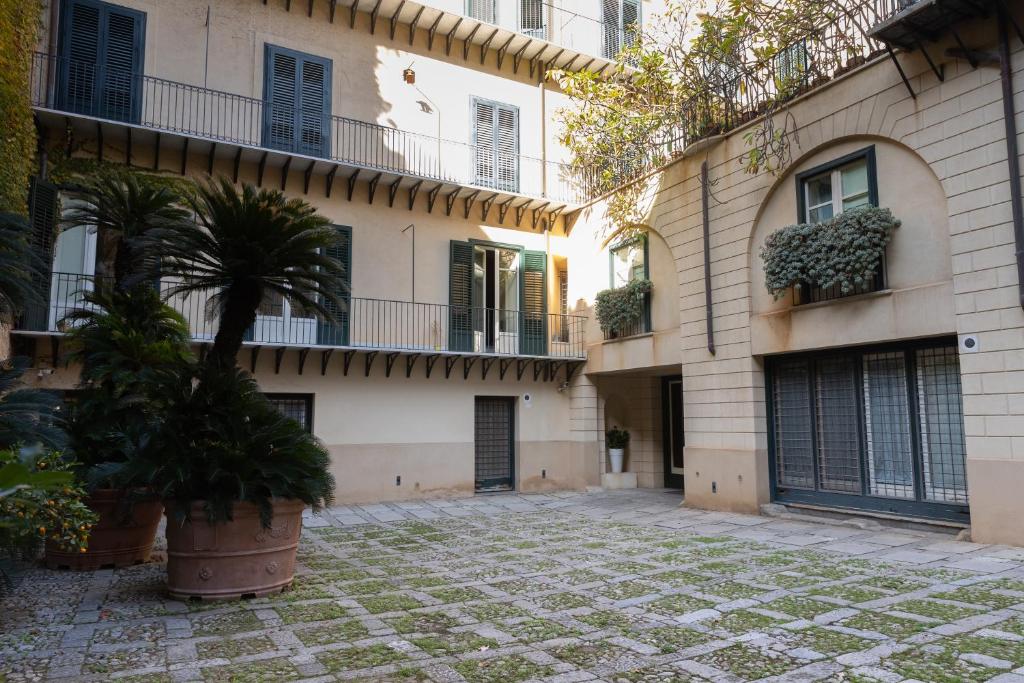 een binnenplaats voor een gebouw met een palmboom bij Dimora Artale Suite in Palermo