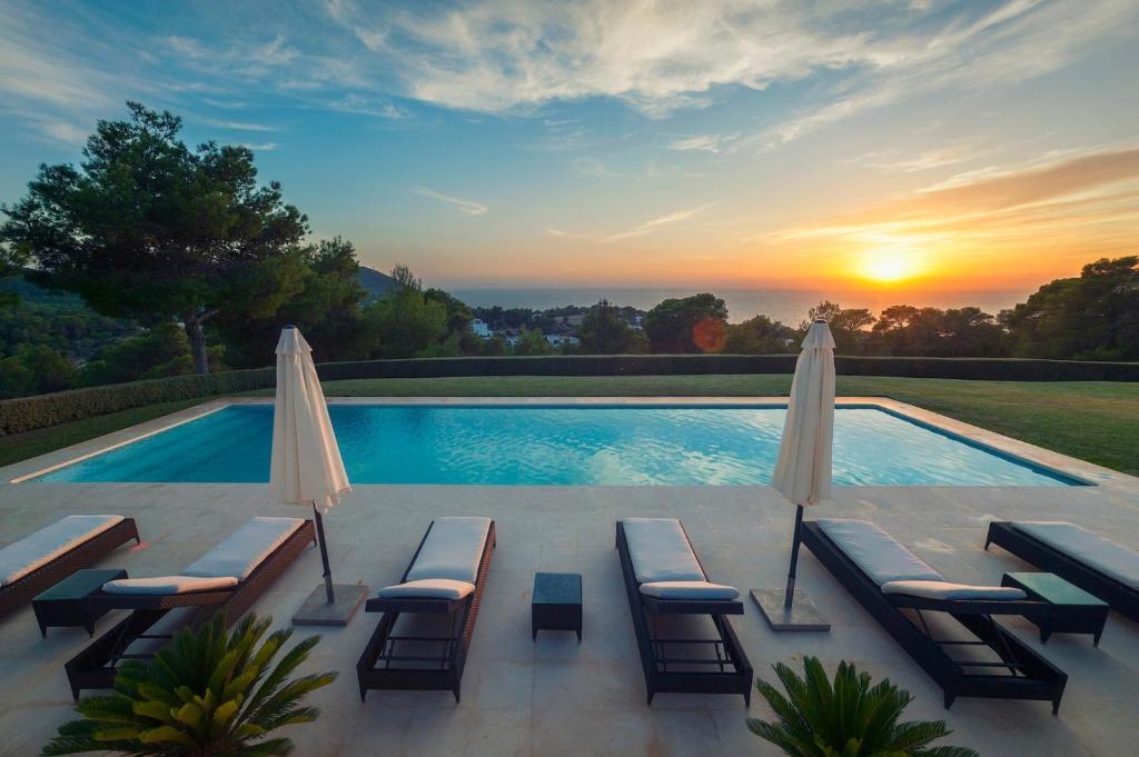 a swimming pool with lounge chairs and a sunset at Stunning Modern Ibiza Villa with Private Pool,1252 in Cala Vadella