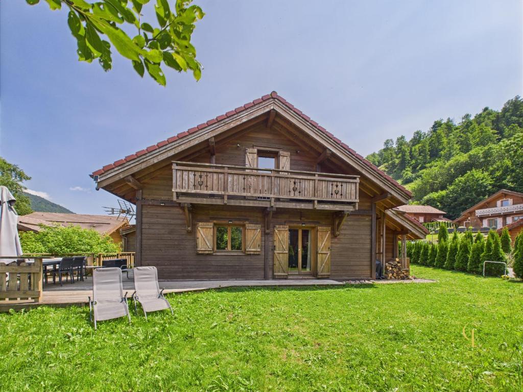 a log house with a deck and chairs in the yard at Le Chalet du Père Michel, Jacuzzi, Sauna, Jardin in La Bresse