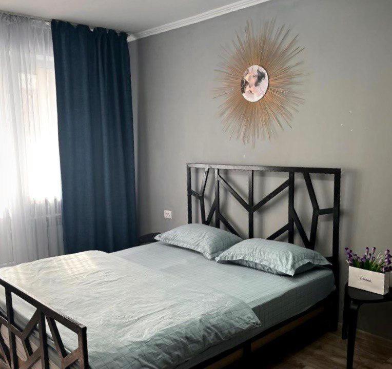 een slaapkamer met een bed met blauwe gordijnen en een spiegel bij Абая 35 1 in Temirtaū