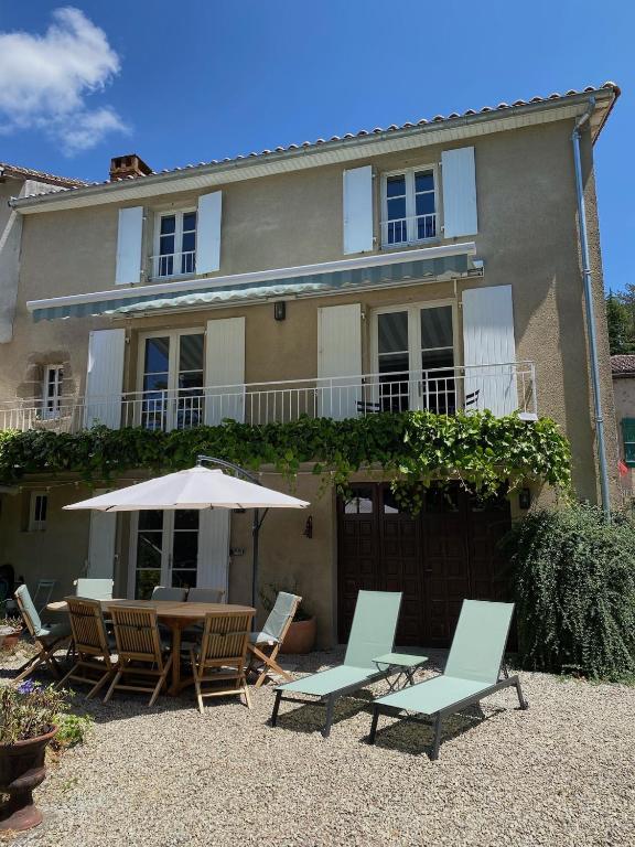 a house with chairs and a table and an umbrella at Le Caprice garden, river and chateau in Saint-Germain-de-Confolens
