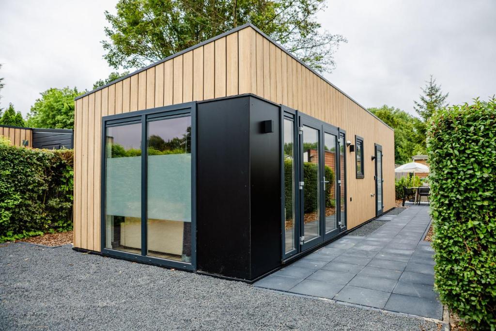 a small building with glass doors on a sidewalk at Mooi Chalet met sauna in hartje Zeeland VP080 in Heinkensand