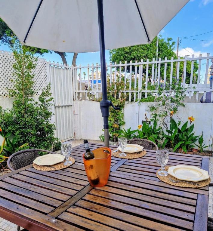 a wooden table with plates and an umbrella at Beach and Surf House in Costa da Caparica