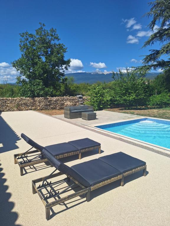 - deux chaises longues à côté de la piscine dans l'établissement Le Portail Vert, à Villes-sur-Auzon