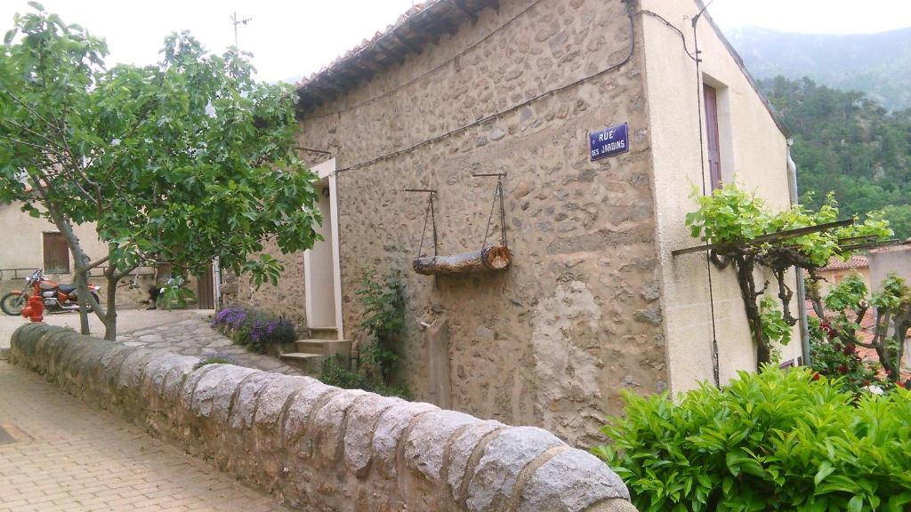 a stone building with a stone wall next to a street at Vernet Jardin in Vernet-les-Bains