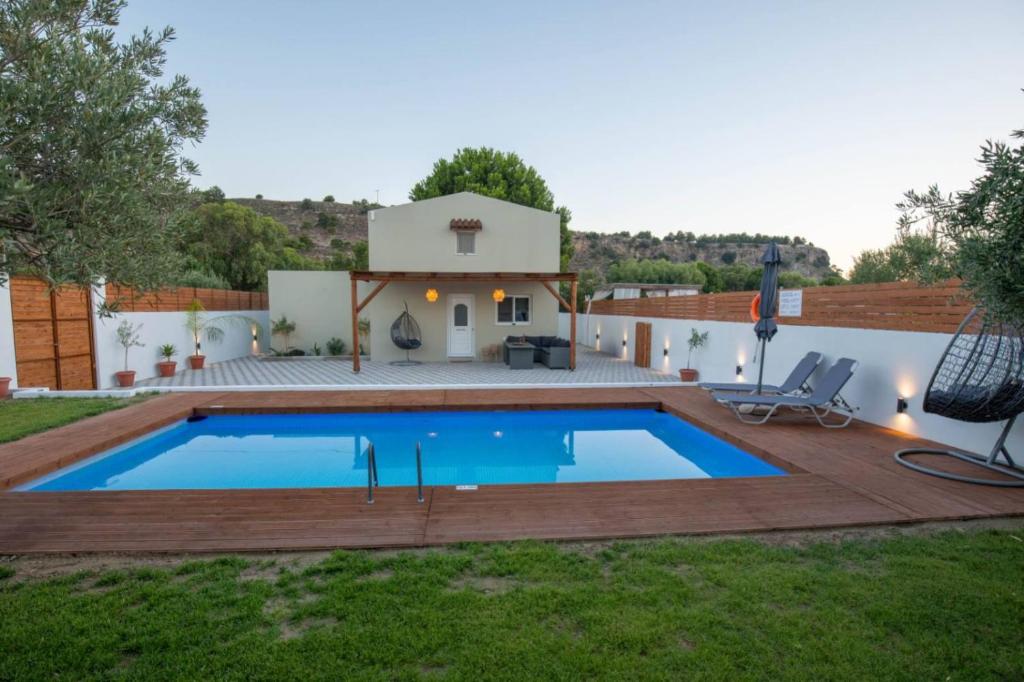 a swimming pool with a deck and a house at Garden Olive Luxury Villa in Archangelos