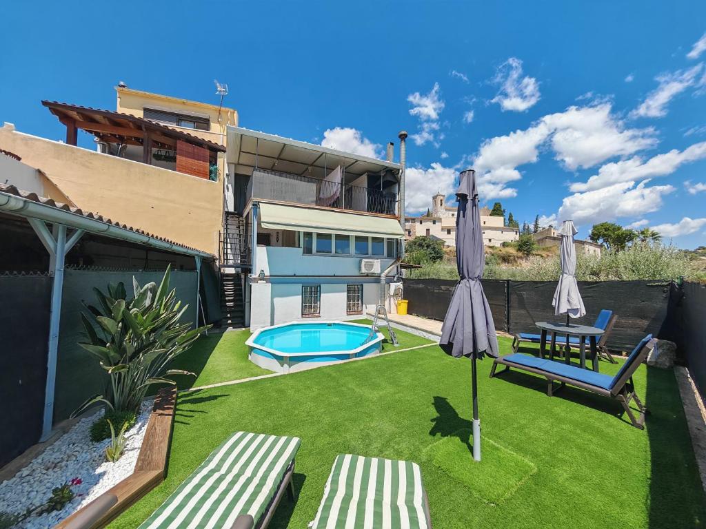 a small backyard with an umbrella and a pool at Casa Joana in Canyelles