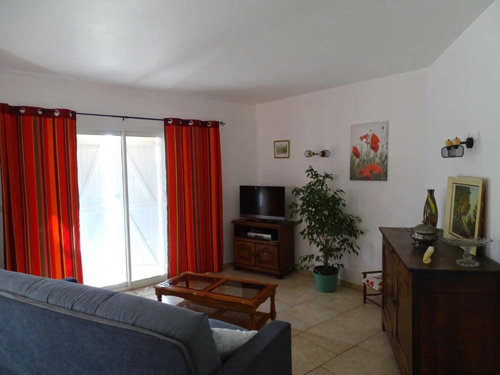 sala de estar con sofá azul y cortinas rojas en Villa bellevue, en Fanjeaux