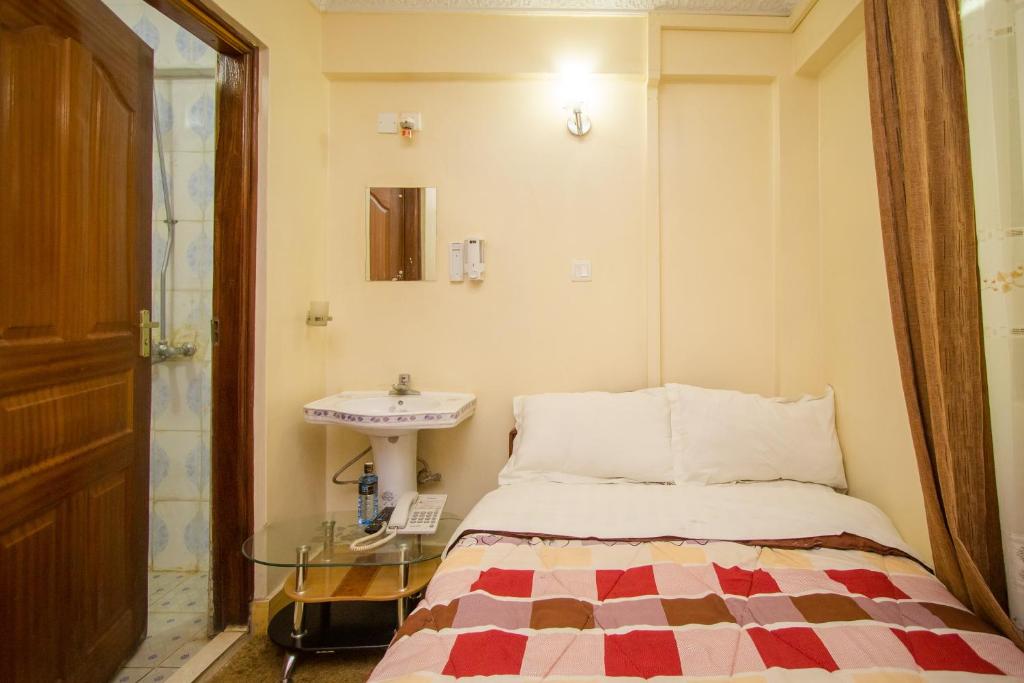 een kleine slaapkamer met een bed en een wastafel bij Shamz Hotel in Isiolo