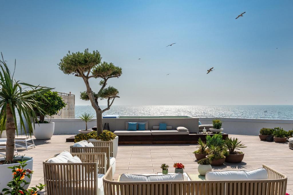 a patio with chairs and a couch and the ocean at La Chiaja art&relais in Castellammare di Stabia
