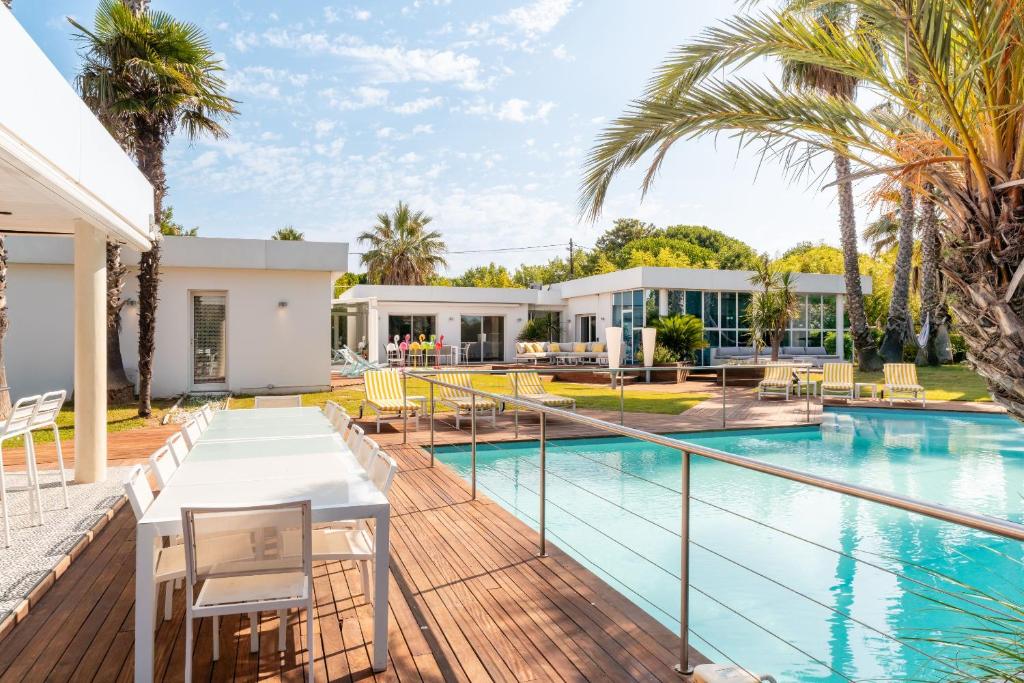 Una terraza al aire libre con una mesa y sillas junto a una piscina. en Villa Summer Wind, en Le Grau d'Agde