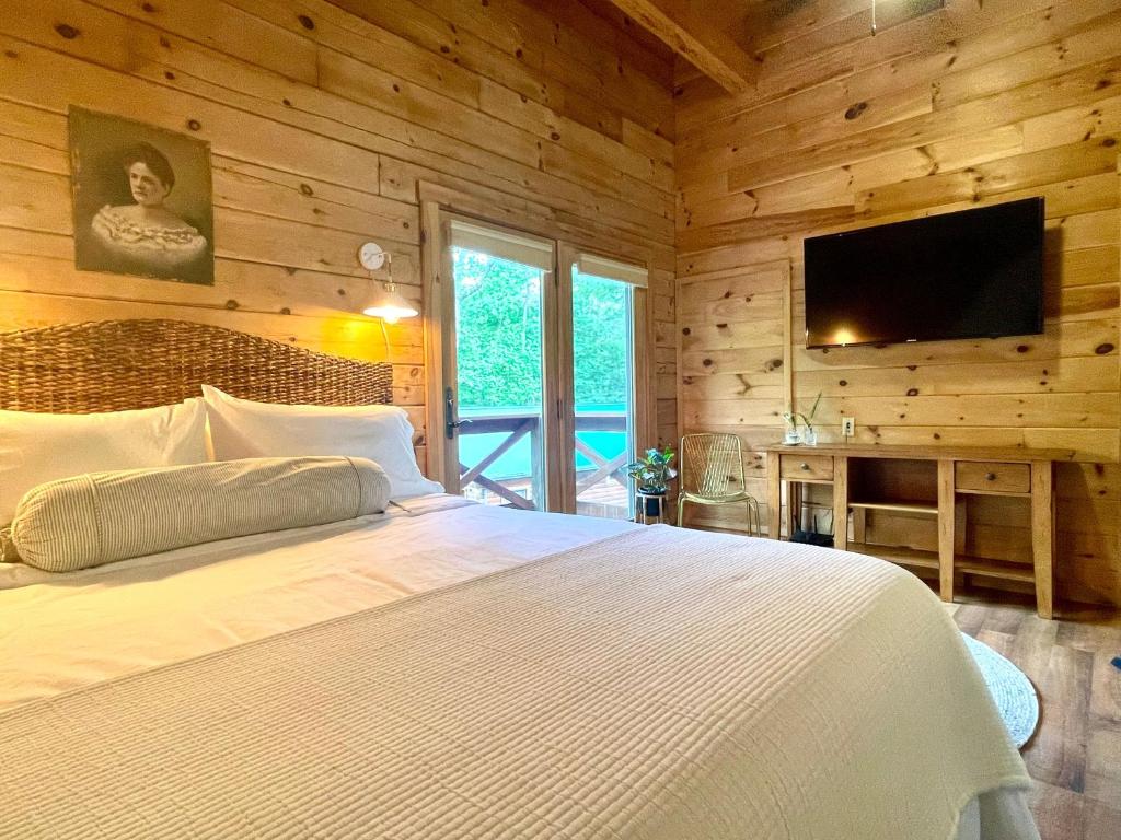 a bedroom with a white bed and a flat screen tv at Mossy Falls Cabin by Leavetown Vacations in Altamont