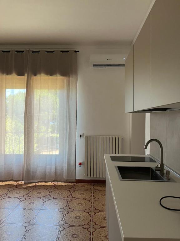 a white kitchen with a sink and a window at Riaci Bay in Tropea