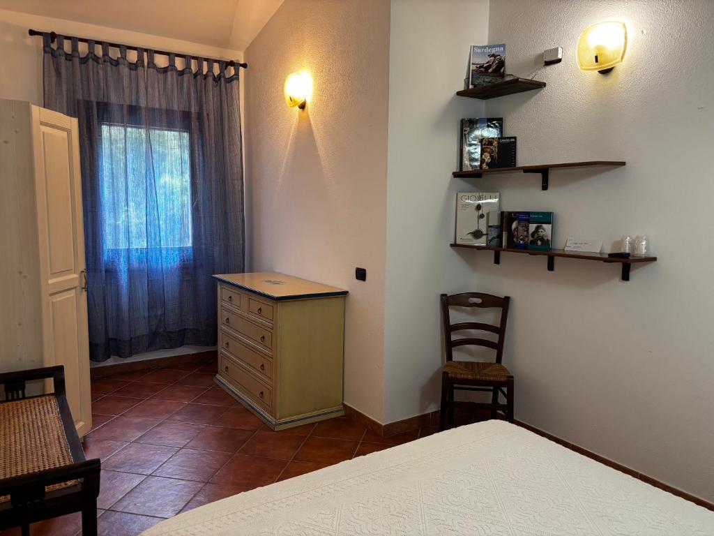 a bedroom with a bed and a dresser and a window at La Borgata - Guest House in Campanedda