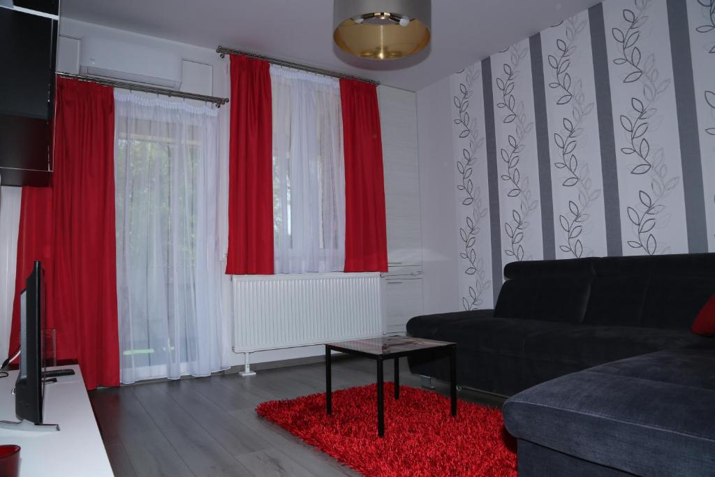ハイドゥソボスローにあるSzofi Apartmanのリビングルーム(赤いカーテン、ソファ付)