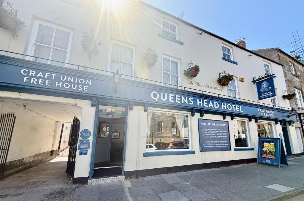 a white building with a sign for a queens head hotel at The Queen's Head in Alnwick