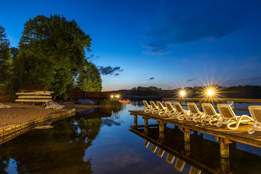 a row of chairs sitting on a dock next to a lake at Hotel Masuria in Łukta