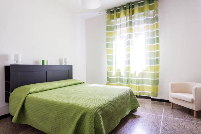 a bedroom with a green bed and a chair at GreenHouseBologna in Bologna