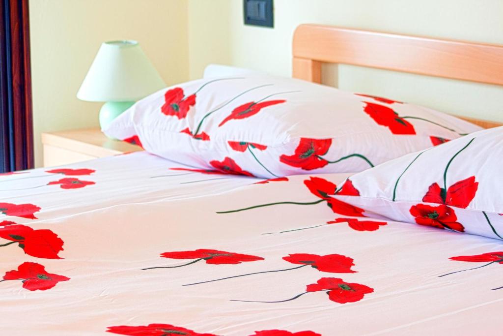 a white bed with red flowers on it at Apartman Orbanići in Orbanići