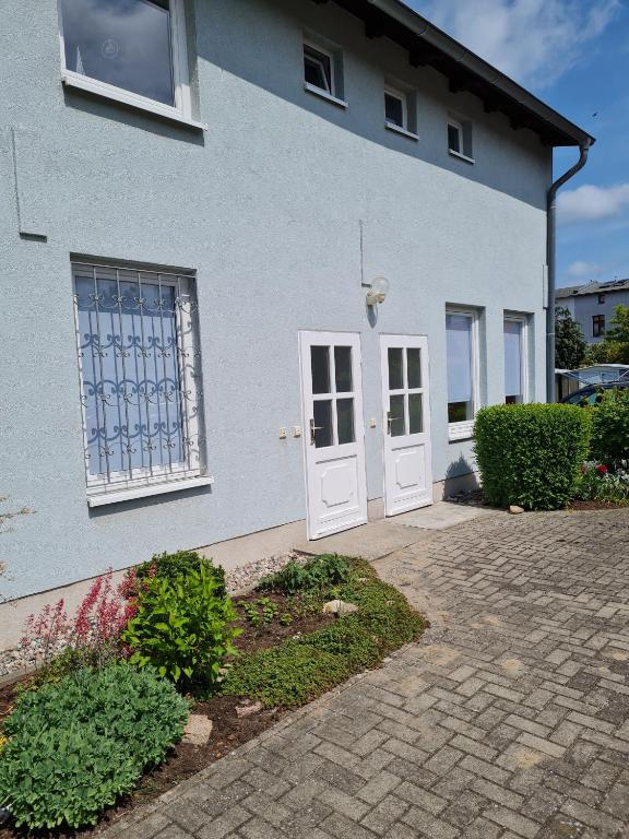 a white house with white doors and a brick driveway at Ferienwohnung Ribnitz-Damgarten in Ribnitz-Damgarten