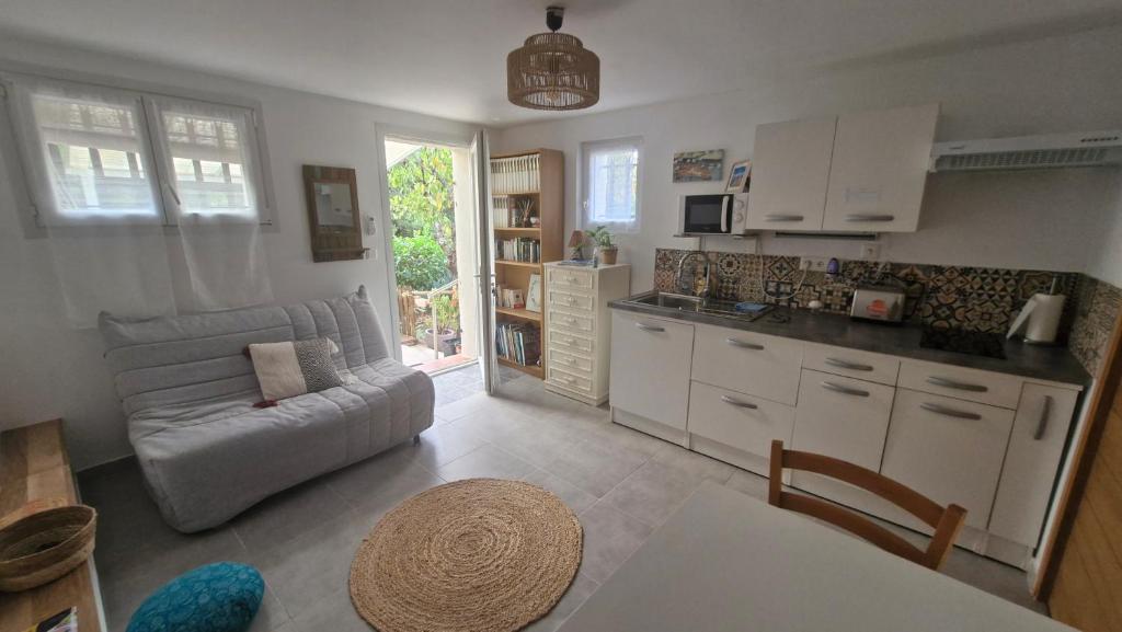 une cuisine et un salon avec un canapé dans l'établissement Studio calme avec jardinet, à Fréjus