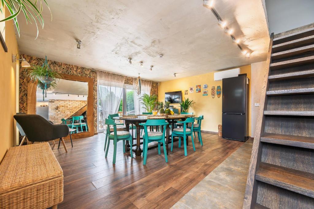 ein Esszimmer mit einem Tisch und grünen Stühlen in der Unterkunft Mano Malibu in Melnragė