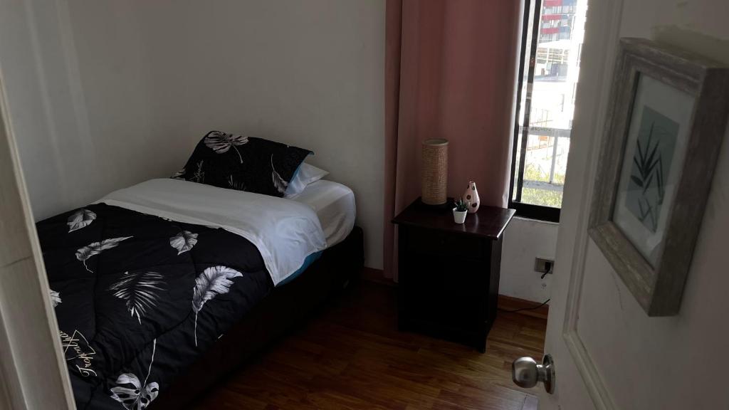 una piccola camera da letto con un letto e una finestra di Departamento antiguo frente al mar a Iquique