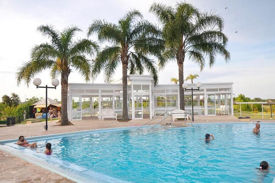 un groupe de personnes dans une piscine bordée de palmiers dans l'établissement Minicasa Ensueño, à Colonia Hocker
