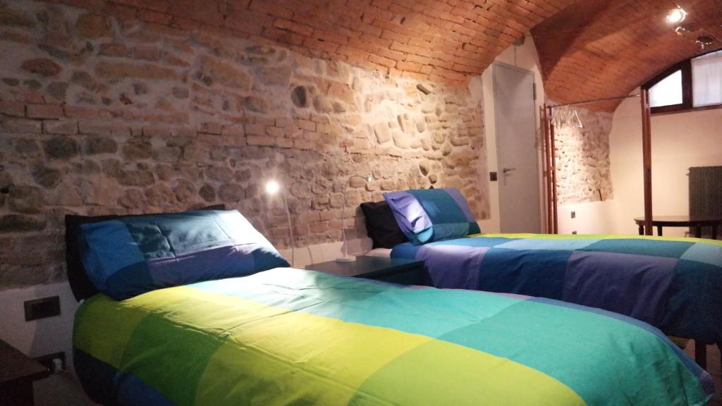 duas camas num quarto com uma parede de pedra em All' Ombra del Portico em Bolonha