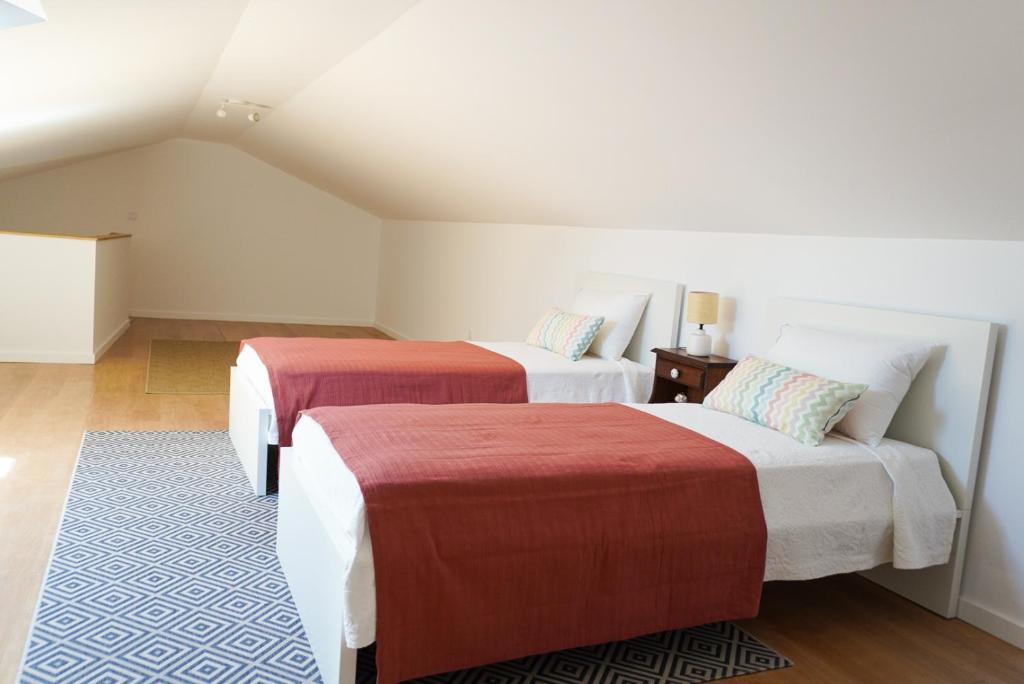 a hotel room with two beds with red and white sheets at Casa das Amoreiras in Vila Franca do Campo