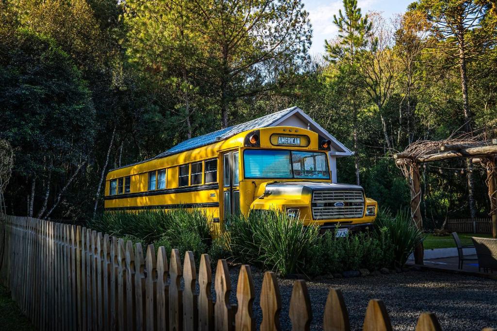 uno scuolabus giallo parcheggiato accanto a una recinzione di American Bus Glamping - Capinzal/SC a Ouro