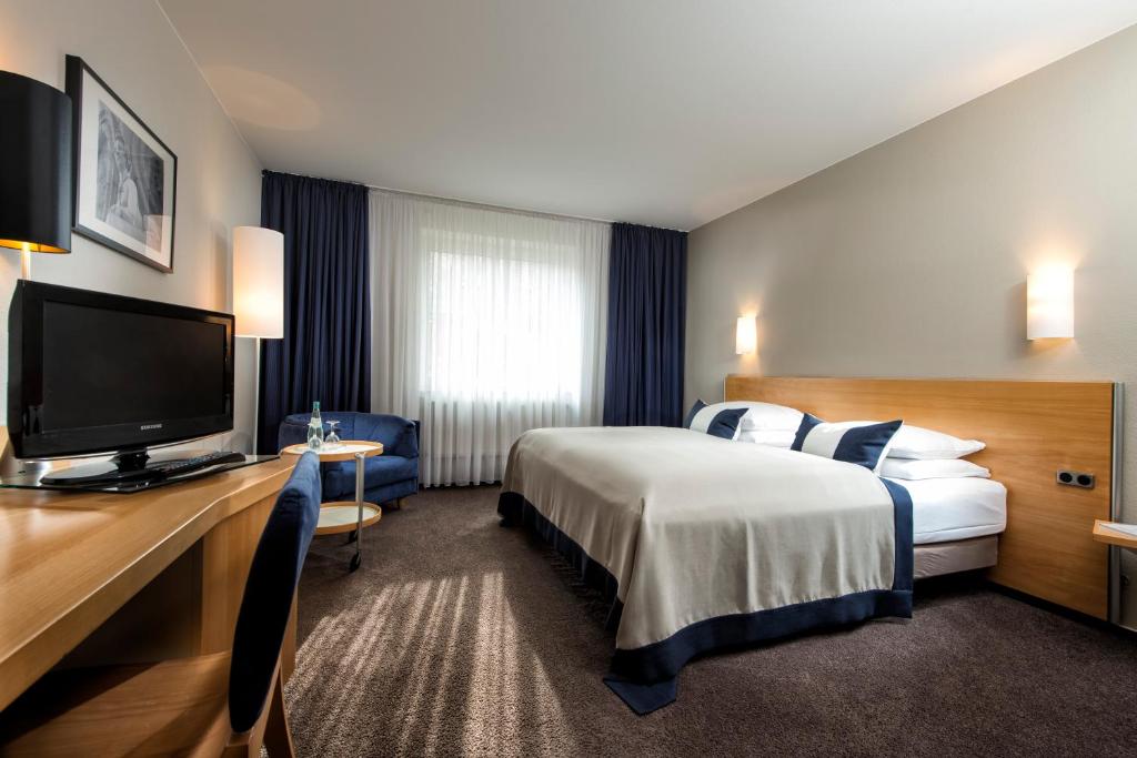a hotel room with a bed and a flat screen tv at Wyndham Garden Potsdam in Potsdam
