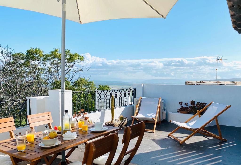 un tavolo e sedie su un patio con ombrellone di Casa Vejer con vistas y garaje a Vejer de la Frontera