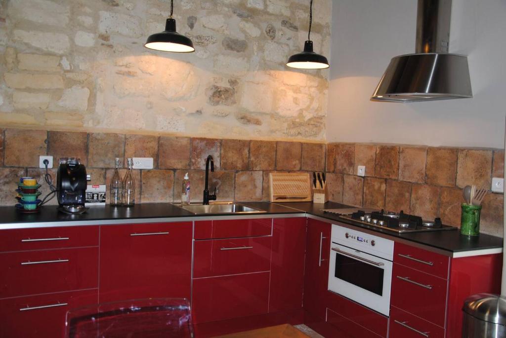 eine Küche mit roten Schränken und einer Steinmauer in der Unterkunft Le Mas de Lucas in Arles