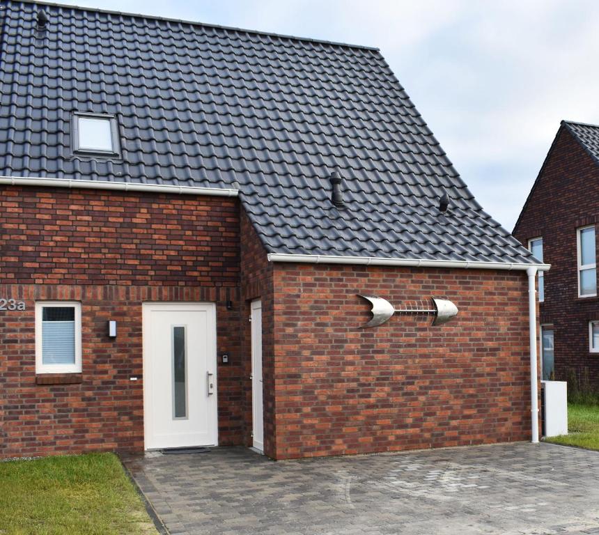 a brick building with a white door and a roof at Windsbraut in Butjadingen
