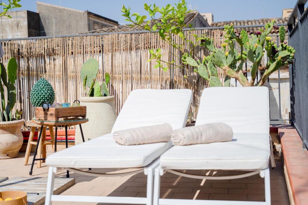 two white chairs on a patio with plants at Casa di charme "Al Moro Avola " in Avola