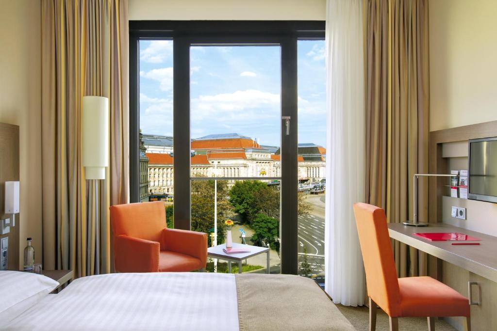 une chambre d'hôtel avec un lit, deux chaises et une fenêtre dans l'établissement IntercityHotel Leipzig, à Leipzig