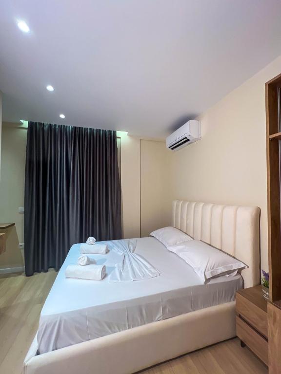 a bedroom with a large white bed with a window at Serenita Hotel in Vlorë