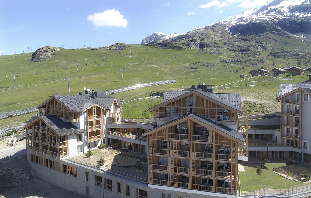 un groupe de bâtiments avec une montagne en arrière-plan dans l'établissement Résidence Phoenix B by Leavetown Vacations, à L'Alpe-d'Huez