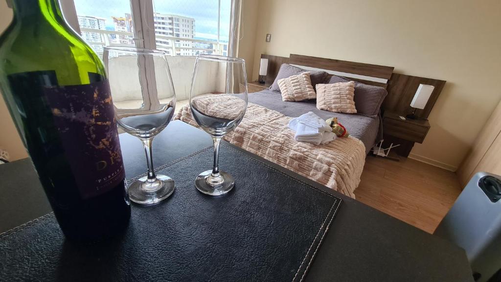 a room with a bed and two wine glasses on a table at Departamento Estudio Central in Temuco