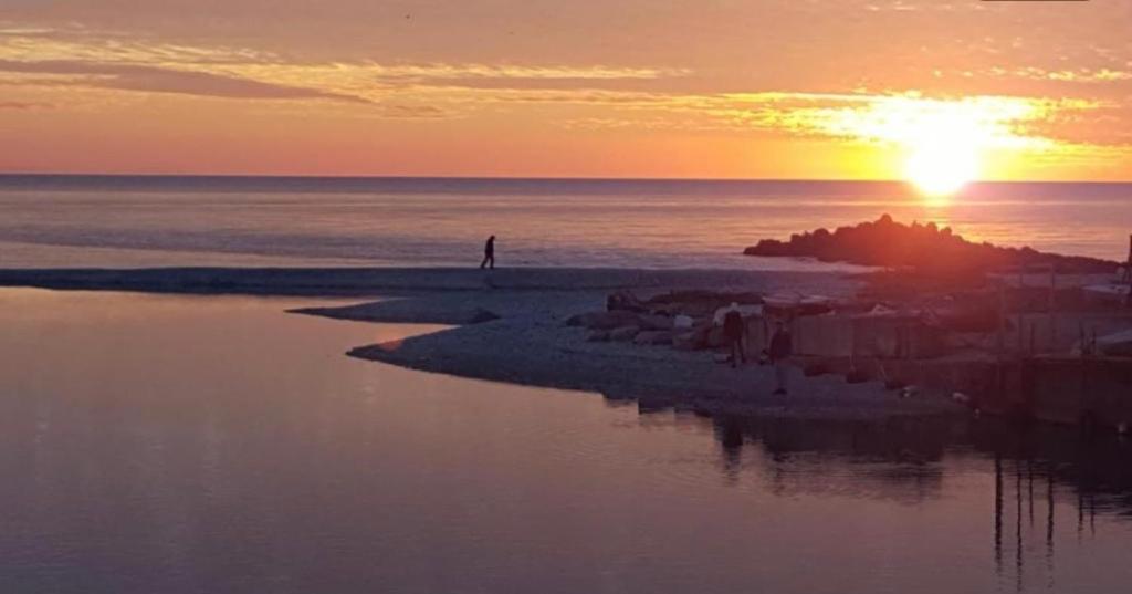 a person standing on the beach at sunset at La Casetta in Marina di Massa