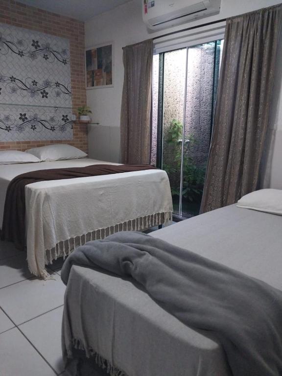 a bedroom with two beds and a window at Casa da isy hospedagem in Natal