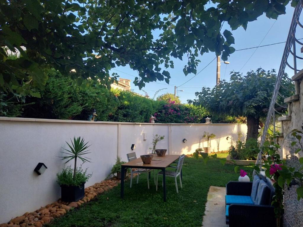 einen Garten mit einem Tisch, Stühlen und einem Zaun in der Unterkunft Maison en rez-de chaussée près du centre ville d'Arles in Arles