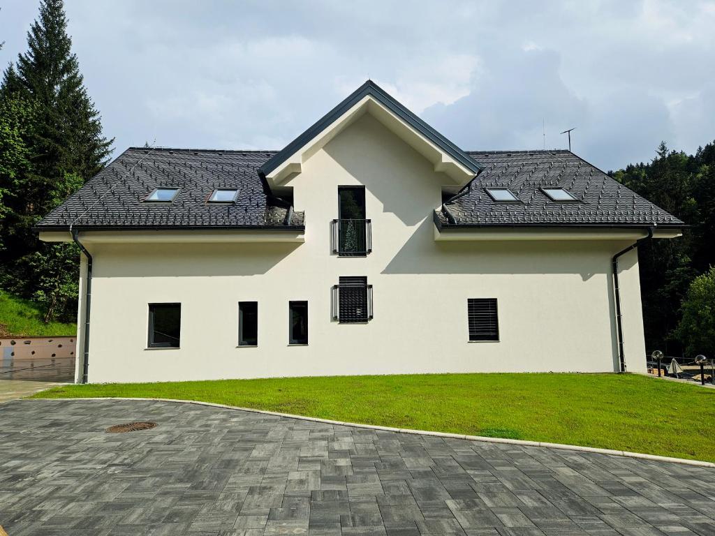 una casa blanca con techo negro en Apartmaji Vouk - sodobni apartmaji v objemu narave - Lukanja - Rogla - Primerno za pare in družine - Sprostitev in aktivno preživljanje prostega časa, en Oplotnica