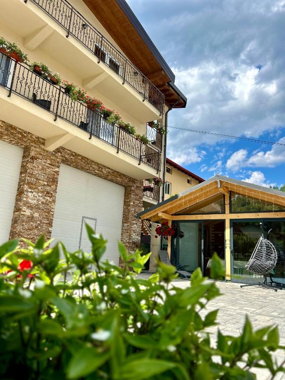 a building with a balcony and a chair on a patio at Pensiunea CUZA in Borşa