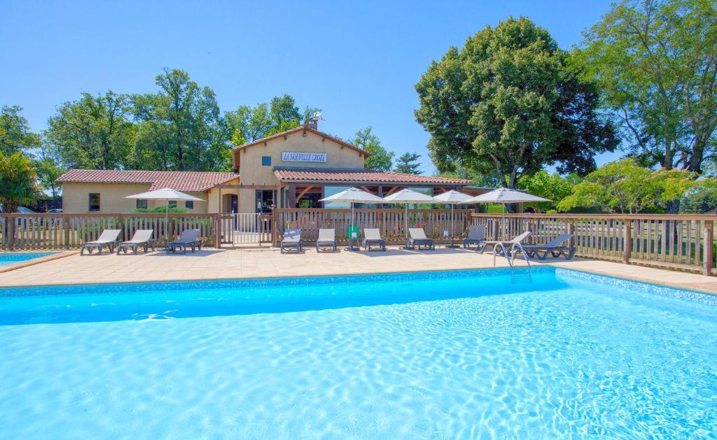 a swimming pool with chairs and a house at Camping Rouffignac-St-Cernin in Ladeymarie