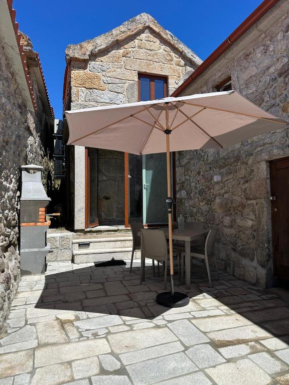 a table with an umbrella in front of a building at Casa de Lamalonga T2 in Campos
