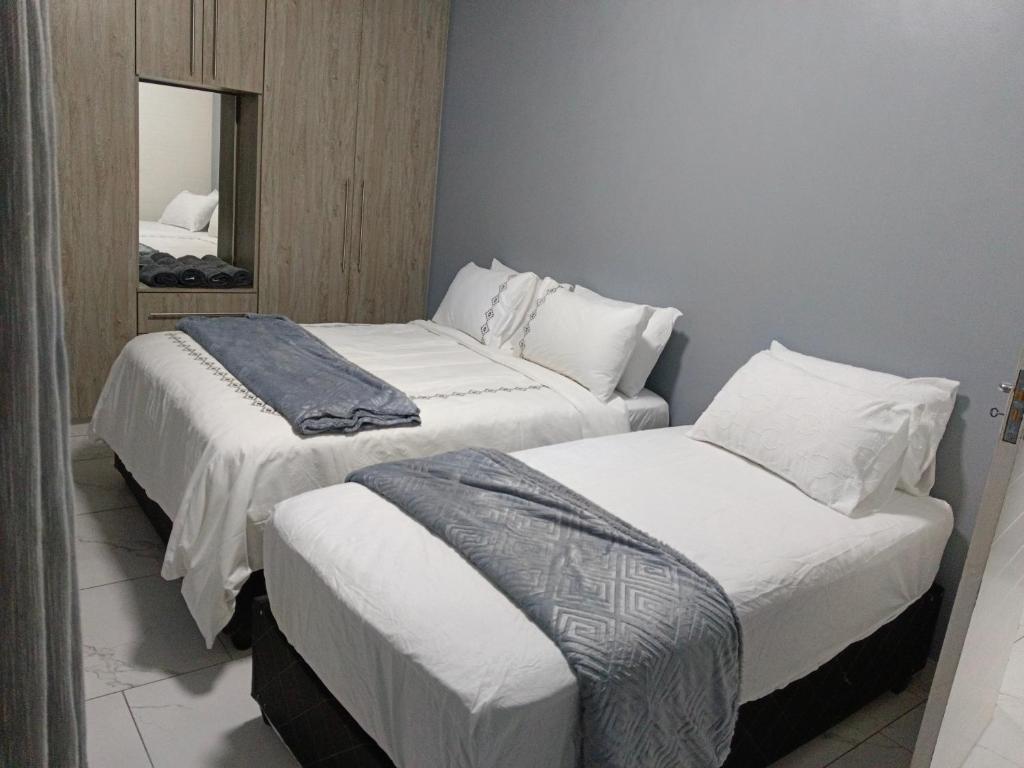 two beds in a room with a mirror at Crompton Apartment 786 in Durban